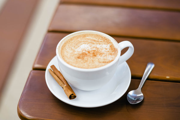 Cup of chai with a cinnamon stick on a wooden table
